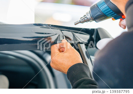 A car wrapping specialist applies a polyurethane film to the car. Detailer PPF 139387795