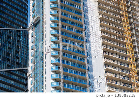 A high-rise building under construction with a tower crane and glass balconies. A high-rise building under construction with a tower crane and glass balconies. 139388219
