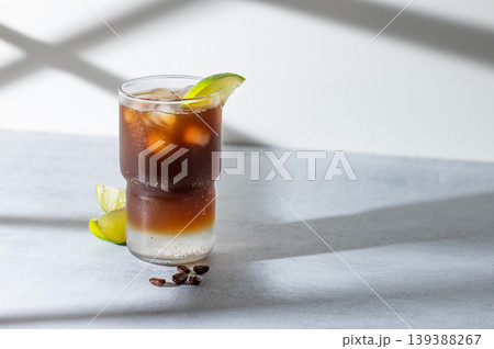 Cold Coffee Tonic Drink With Lime and Ice on light background with shadows 139388267
