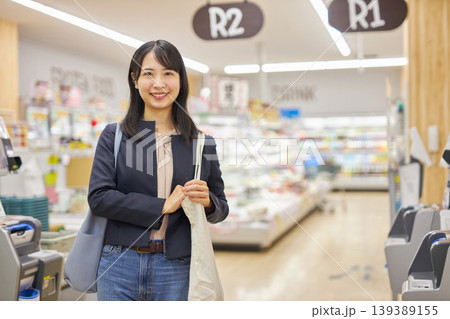 セルフレジで清算を済ませてエコバッグを肩に描ける若い女性 セルフレジで清算を済ませてエコバッグを肩に描ける若い女性 139389155