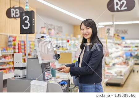 セルフレジでスマートフォン決済をする若い女性 セルフレジでスマートフォン決済をする若い女性 139389360