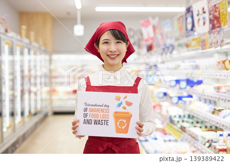 スーパーマーケットの商品の前で食品ロスのプラカードを持つ若い女性 スーパーマーケットの商品の前で食品ロスのプラカードを持つ若い女性 139389422