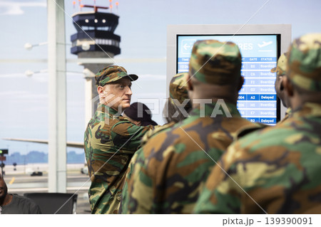 Close up of military squad in airport terminal looking at plane departure timetable FIDS display. Diverse army soldiers in airport lobby discussing about flight schedule information 139390091