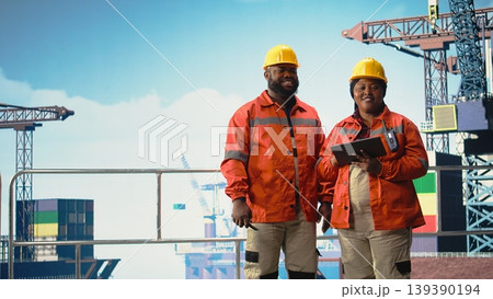 Happy offshore platform engineering team monitoring operations on oil production barge. Joyous drilling rig ship crew wearing safety gear reviewing energy operations, 139390194