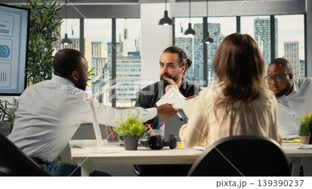 Employees reviewing documentation and performance reports. Colleagues group in a professional office setting collaborate on planning, projections and market research. Employees reviewing documentation and performance reports. Colleagues group in a professional office setting collaborate on planning, projections and market research. 139390237