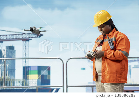 Drilling barge engineer using drone for quick overview and evaluation of hard to reach areas. African american offshore platform worker uses remote control UAV for preventive maintenance planning Drilling barge engineer using drone for quick overview and evaluation of hard to reach areas. African american offshore platform worker uses remote control UAV for preventive maintenance planning 139390288