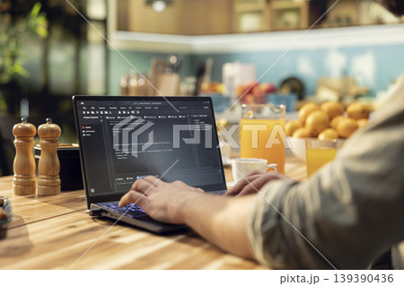 One person coding on laptop in a kitchen representing remote work in IT and software development. Programmer writes source code and uses command-line tools, highlighting engineering at home. One person coding on laptop in a kitchen representing remote work in IT and software development. Programmer writes source code and uses command-line tools, highlighting engineering at home. 139390436