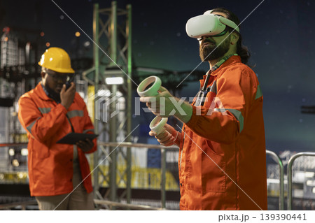 Offshore platform worker using virtual reality technology late at night to configure ship management systems. Drilling rig expert doing seabed analysis using VR headset equipment Offshore platform worker using virtual reality technology late at night to configure ship management systems. Drilling rig expert doing seabed analysis using VR headset equipment 139390441