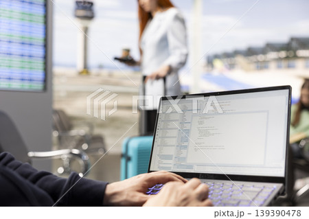 Man digital nomad, focused on programming, system development on laptop, in the airport terminal, surrounded by passengers. Coding and data processing via flexible job mobility. Man digital nomad, focused on programming, system development on laptop, in the airport terminal, surrounded by passengers. Coding and data processing via flexible job mobility. 139390478