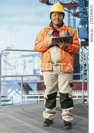 Portrait of smiling offshore platform employee using performance management program to reduce downtime. Happy woman uses laptop program integrating sensor readings to manage operations Portrait of smiling offshore platform employee using performance management program to reduce downtime. Happy woman uses laptop program integrating sensor readings to manage operations 139390622