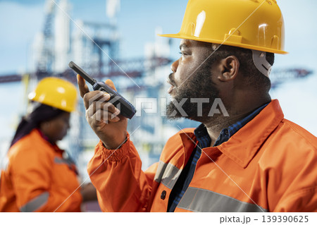 Closeup of fossil fuel company manager on drilling barge uses walkie talkie to ensure uninterrupted communication with workers. Man on offshore rig platform transmits instructions through radio device Closeup of fossil fuel company manager on drilling barge uses walkie talkie to ensure uninterrupted communication with workers. Man on offshore rig platform transmits instructions through radio device 139390625