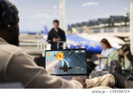 Excited gamer playing online competition game in airport terminal, strategy and interactive action while waiting plane. Modern travel moment with gaming as relaxation and entertainment. Excited gamer playing online competition game in airport terminal, strategy and interactive action while waiting plane. Modern travel moment with gaming as relaxation and entertainment. 139390724