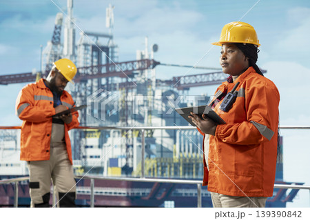Offshore platform experts using monitoring program on tablet to track carbon footprint, protecting environment. African american engineers conduct environmental risk assessment for drilling rig 139390842