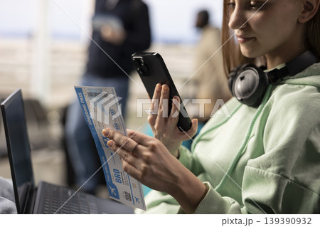 Gen z girl using phone to scan boarding pass information in airport lounge, air travel and nomadic lifestyle concept. Location independent freelancer with flexible career, job mobility. Gen z girl using phone to scan boarding pass information in airport lounge, air travel and nomadic lifestyle concept. Location independent freelancer with flexible career, job mobility. 139390932
