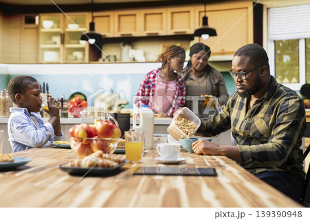 Parents and children starting the day with a healthy breakfast of pastry and eggs, cozy morning light in the kitchen. Family bonding, warmth and the joy of sharing delicious food together. Parents and children starting the day with a healthy breakfast of pastry and eggs, cozy morning light in the kitchen. Family bonding, warmth and the joy of sharing delicious food together. 139390948