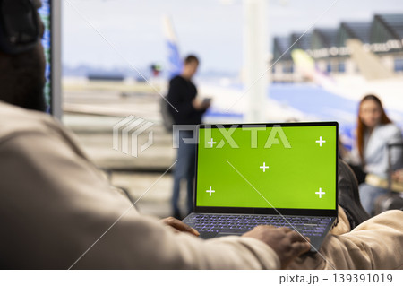 Isolated green screen with black guy digital nomad in airport lounge, seated near the boarding gate and working on laptop. Nomadic lifestyle, flexible job and international air travel. Isolated green screen with black guy digital nomad in airport lounge, seated near the boarding gate and working on laptop. Nomadic lifestyle, flexible job and international air travel. 139391019