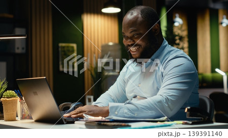 Excited african american man receiving good news for career opportunity, being proud of his breakthrough and accomplishment in the office late at night. Delighted about new deal. 139391140