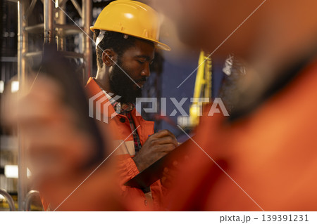 Industrial worker monitoring offshore drilling rig operation with tablet, focusing on professional fossil fuels and oil extraction on a platform. Natural gas and petrol for the oil industry. 139391231