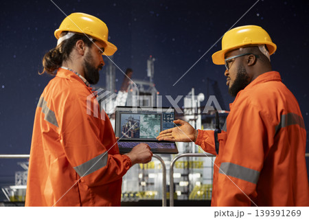 Offshore platform engineering team coworkers use laptop to survey geological data and do digital mapping. Drilling ship teamworking colleagues evaluate seabed topography maps for site assessment 139391269
