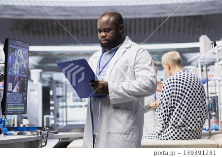African american man records clinical trial data during a drug study with a patient, documenting reactions and dosage effects contributing to product development and pharmacology research. 139391281