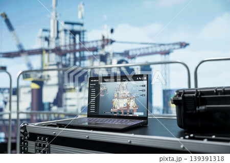 Close up of laptop on offshore platform with software interface used to track production efficiency. Notebook on drilling barge deck with program dashboard used to check equipment sensor readings Close up of laptop on offshore platform with software interface used to track production efficiency. Notebook on drilling barge deck with program dashboard used to check equipment sensor readings 139391318
