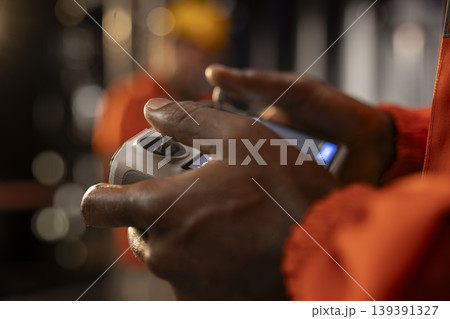 Close up of offshore worker uses drone for maintenance and inspection of drilling platform, integrating UAV technology and remote control systems for efficient oil and petroleum extraction. Close up of offshore worker uses drone for maintenance and inspection of drilling platform, integrating UAV technology and remote control systems for efficient oil and petroleum extraction. 139391327