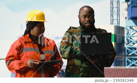 Military personnel stationed on offshore rig evaluating surveillance footage. Soldier provides protection to drilling barge and engineer controlling remote systems with devices Military personnel stationed on offshore rig evaluating surveillance footage. Soldier provides protection to drilling barge and engineer controlling remote systems with devices 139391349