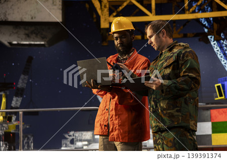 Soldier in uniform operate communication devices during a maritime mission with engineer, providing security for offshore platform logistics and drilling rig protection operations. Soldier in uniform operate communication devices during a maritime mission with engineer, providing security for offshore platform logistics and drilling rig protection operations. 139391374