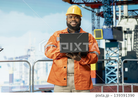 Portrait of smiling offshore platform specialist supervises deck operations, ensuring compliance with safety protocols. Joyous man working for gas company does preventative maintenance on drilling rig Portrait of smiling offshore platform specialist supervises deck operations, ensuring compliance with safety protocols. Joyous man working for gas company does preventative maintenance on drilling rig 139391390