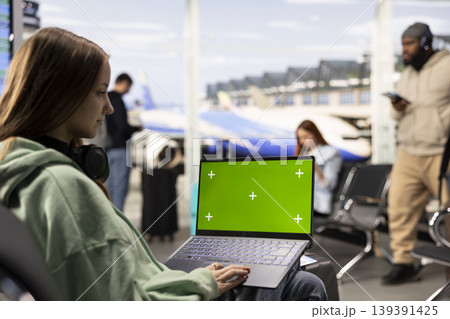Green screen laptop with African American travelers in busy airport waiting area before flight departure. Luggage and boarding procedures in the background, nomadic lifestyle. 139391425