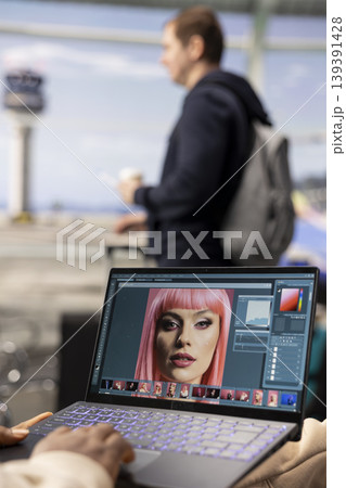 Man photo editor, reviewing images materials, digital nomad, in airport lounge, using photo editing software for editorial production before boarding. Nomadic lifestyle, remote job. 139391428