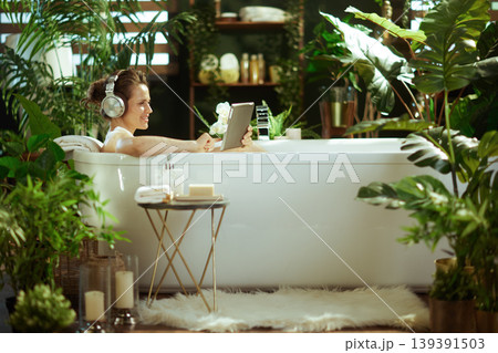 Woman with Headphones Enjoying Spa Bath & Tablet 139391503