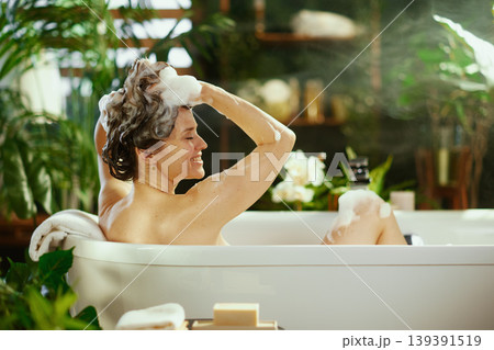 Smiling Woman Relaxing with Hair Wash in Bathtub Smiling Woman Relaxing with Hair Wash in Bathtub 139391519
