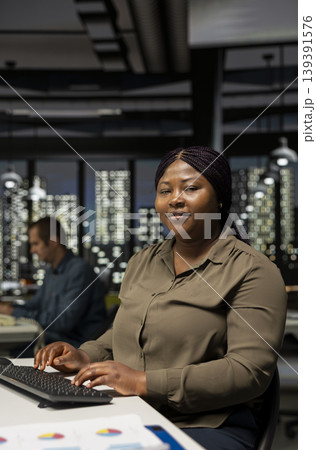 Video creator woman editing a music video on dual monitors in creative office, multitasking between timeline editing and color grading. Professional editor uses tech tools and digital software. 139391576