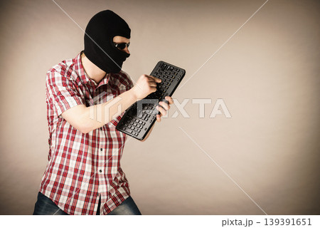 Man wearing balaclava holding keyboard Man wearing balaclava holding keyboard 139391651