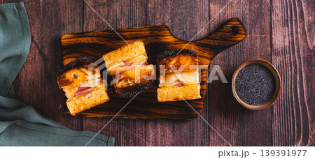 Baked burgers with cheese and ham sprinkled with poppy seeds on a board top view web banner Baked burgers with cheese and ham sprinkled with poppy seeds on a board top view web banner 139391977
