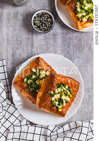 Mini puff pastry tarts with egg and green onions on a plate on the table top and vertical view Mini puff pastry tarts with egg and green onions on a plate on the table top and vertical view 139391987