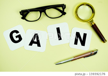GAIN alphabet letters with magnifying glass, eye glasses and pen on yellow background GAIN alphabet letters with magnifying glass, eye glasses and pen on yellow background 139392176