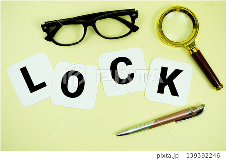 LOCK alphabet letters with magnifying glass, eye glasses and pen on yellow background 139392246