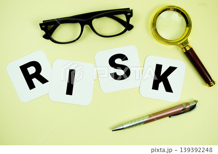 RISK alphabet letters with magnifying glass, eye glasses and pen on yellow background RISK alphabet letters with magnifying glass, eye glasses and pen on yellow background 139392248