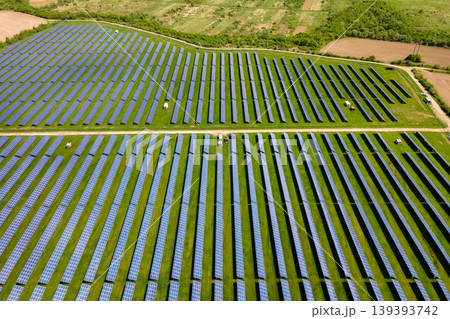 Aerial view of big sustainable electric power plant with many rows of solar photovoltaic panels for producing clean ecological electrical energy. Renewable electricity with zero emission concept. Aerial view of big sustainable electric power plant with many rows of solar photovoltaic panels for producing clean ecological electrical energy. Renewable electricity with zero emission concept. 139393742