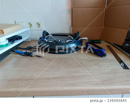 Robot vacuum cleaner disassembled on workbench with repair tools and parts Robot vacuum cleaner disassembled on workbench with repair tools and parts 139393845