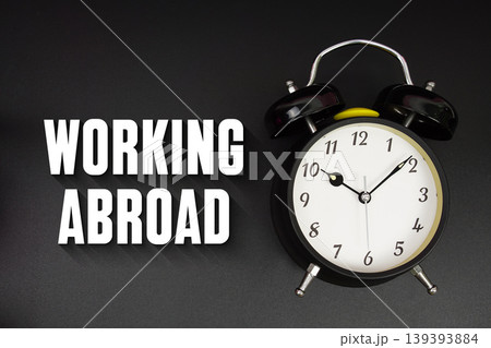 Working Abroad text with alarm clock on black background Working Abroad text with alarm clock on black background 139393884