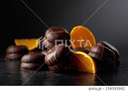 Chocolate dessert with slices of fresh oranges on a black background. 139393992