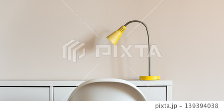 Minimal interior with yellow desk lamp on cabinet and chair Minimal interior with yellow desk lamp on cabinet and chair 139394038