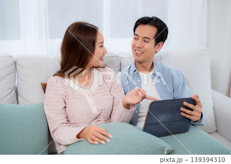 Happy asian couple video call on tablet together in living room at home. Happy asian couple video call on tablet together in living room at home. 139394310