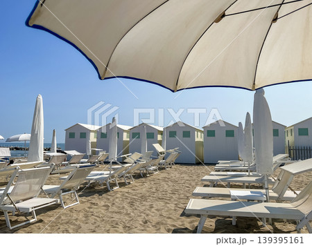 Beach Lounge Chairs and Umbrellas with Coastal Cabins in Lido di Venezia, Italy. 139395161