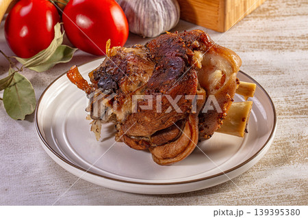 Roasted pork knuckle with crispy skin served with garlic and tomatoes Roasted pork knuckle with crispy skin served with garlic and tomatoes 139395380