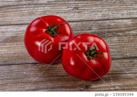 Two ripe red tomatoes on a rustic wooden table Two ripe red tomatoes on a rustic wooden table 139395394