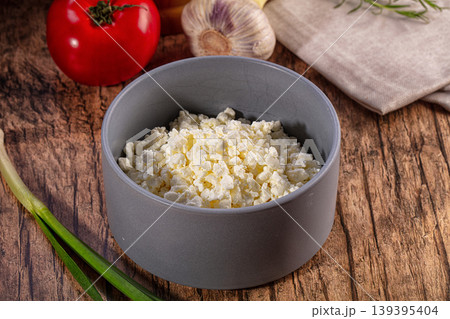 Fresh cottage cheese in a grey bowl with tomato, garlic, and green onion on a rustic wooden table Fresh cottage cheese in a grey bowl with tomato, garlic, and green onion on a rustic wooden table 139395404
